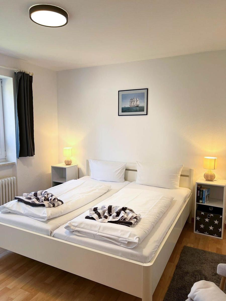 Schlafzimmer mit Doppelbett, zwei Nachttischen und Wandbild mit Segelschiff.