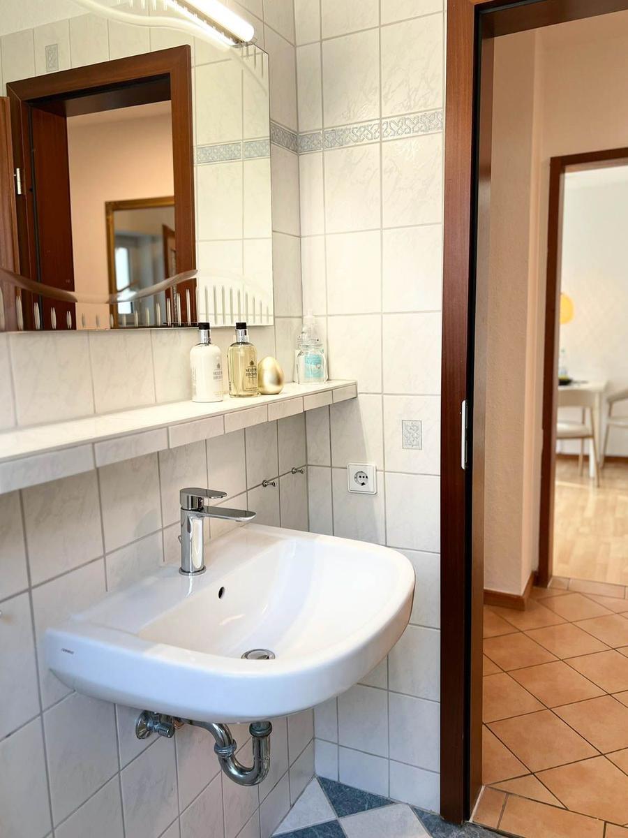 Bad mit Waschbecken, Spiegel und Handtüchern