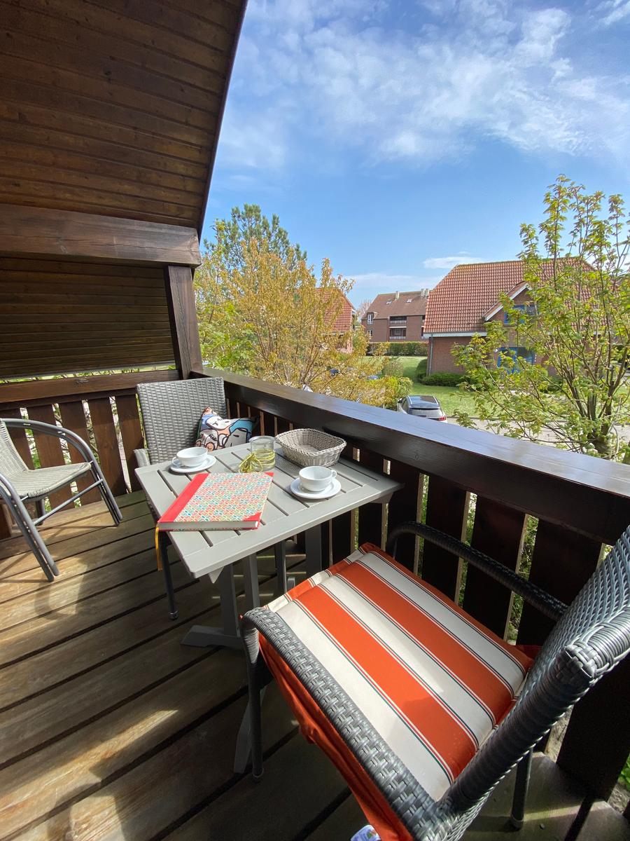 Terrasse mit Tisch, Stühlen und Blick auf Häuser und Bäume.