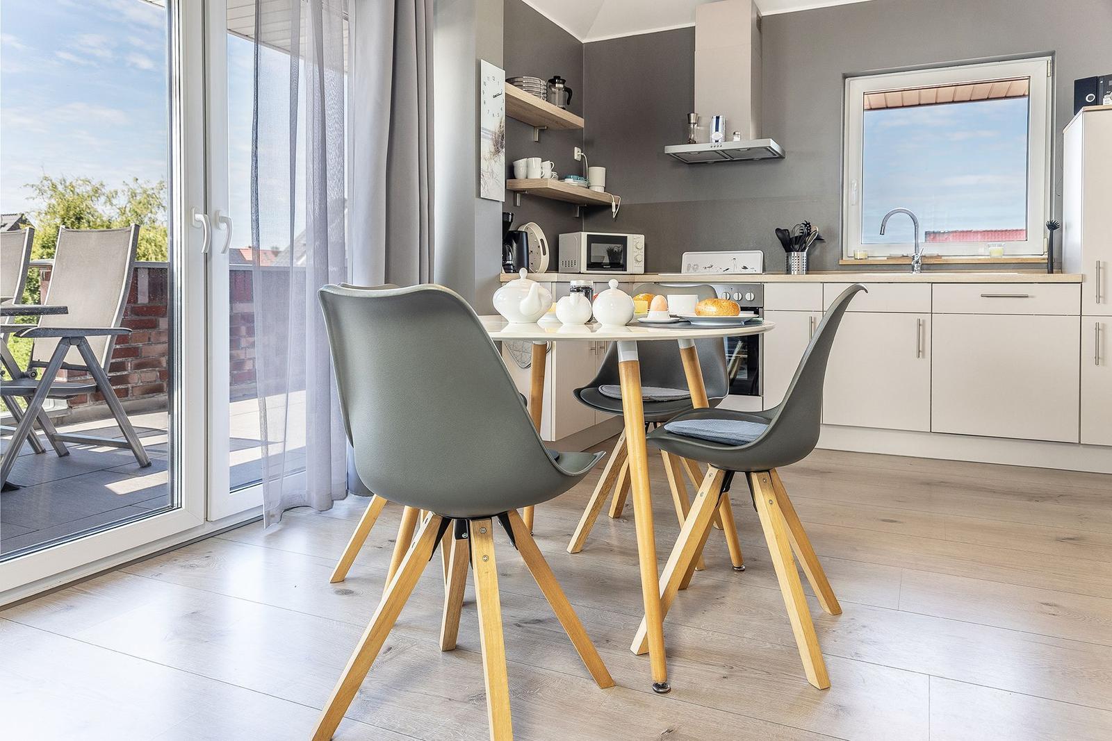 Kitchen with dining area and terrace. Table with chairs, window, and balcony door.