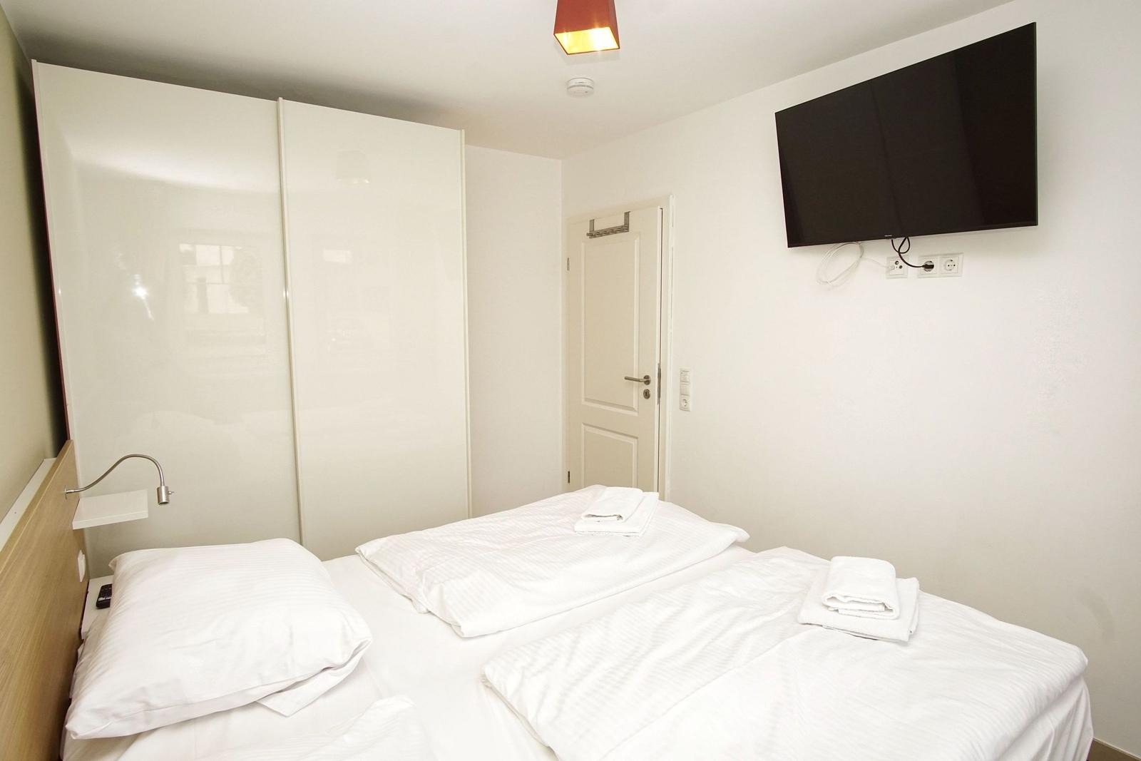 Zimmer mit Doppelbett, Schrank und Wandfernseher