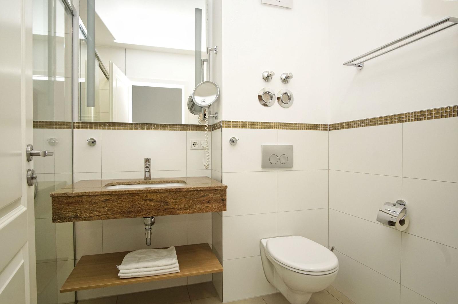 Bad mit Waschbecken, Spiegel, Toilette und Dusche.