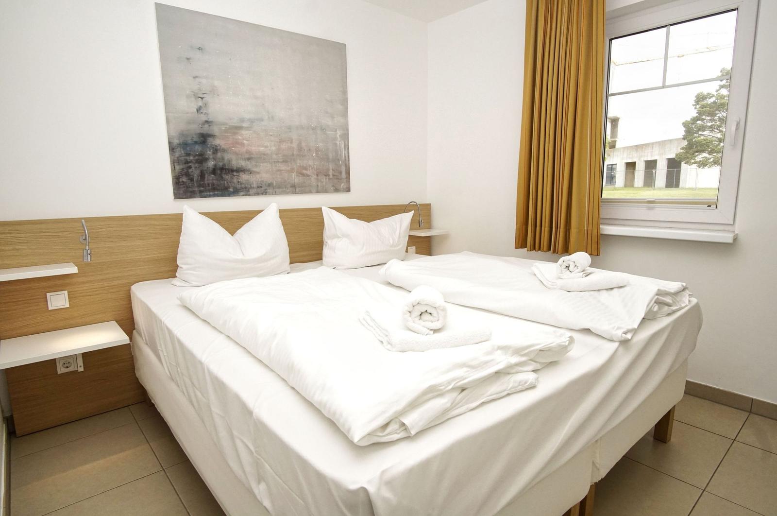 Bedroom with double bed, window, and wall art.