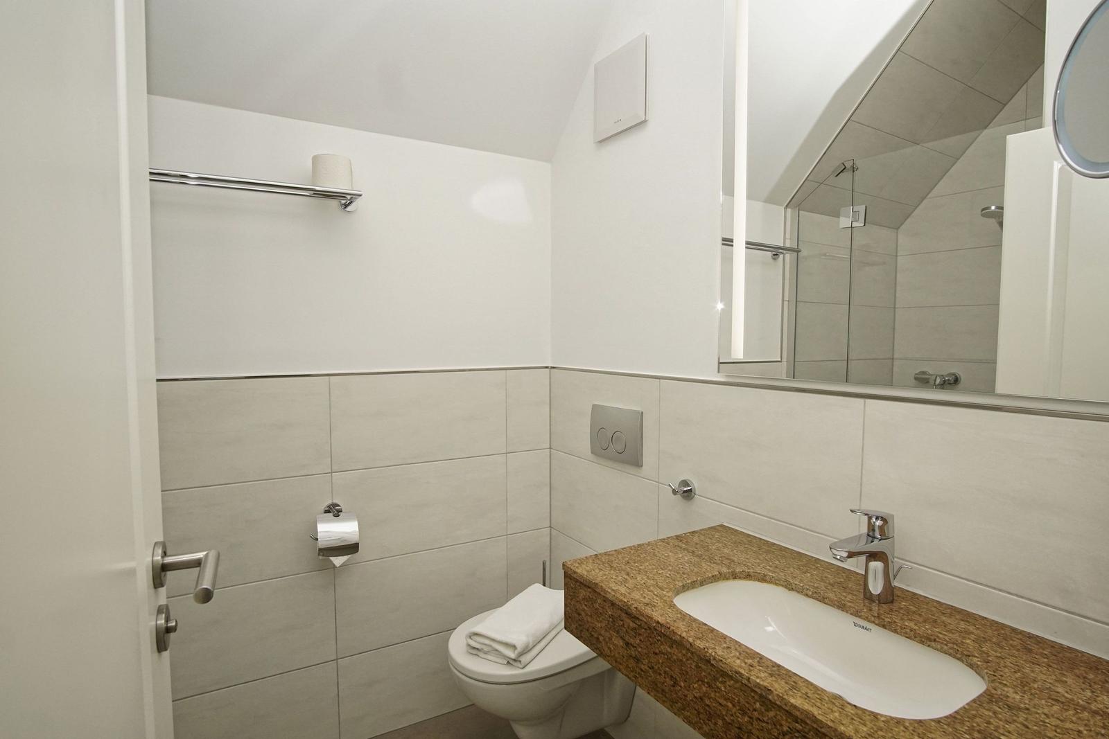 Badezimmer mit Waschbecken, Toilette und Dusche.