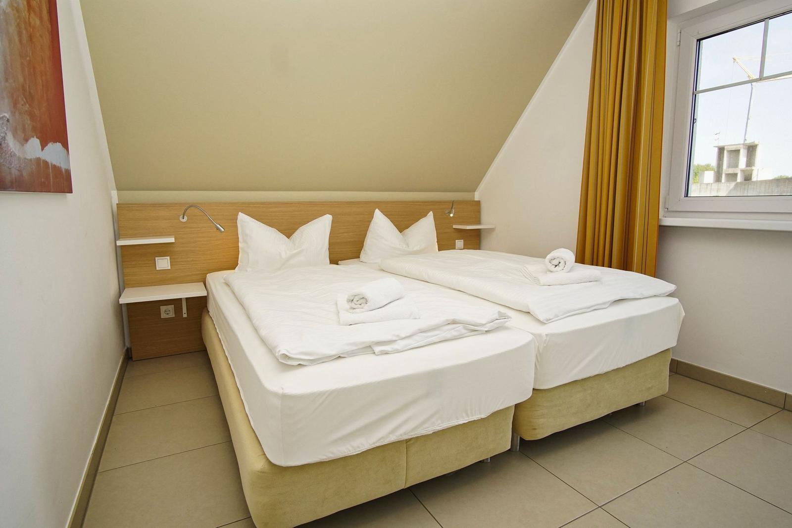 Room with two beds, window, and yellow curtains.