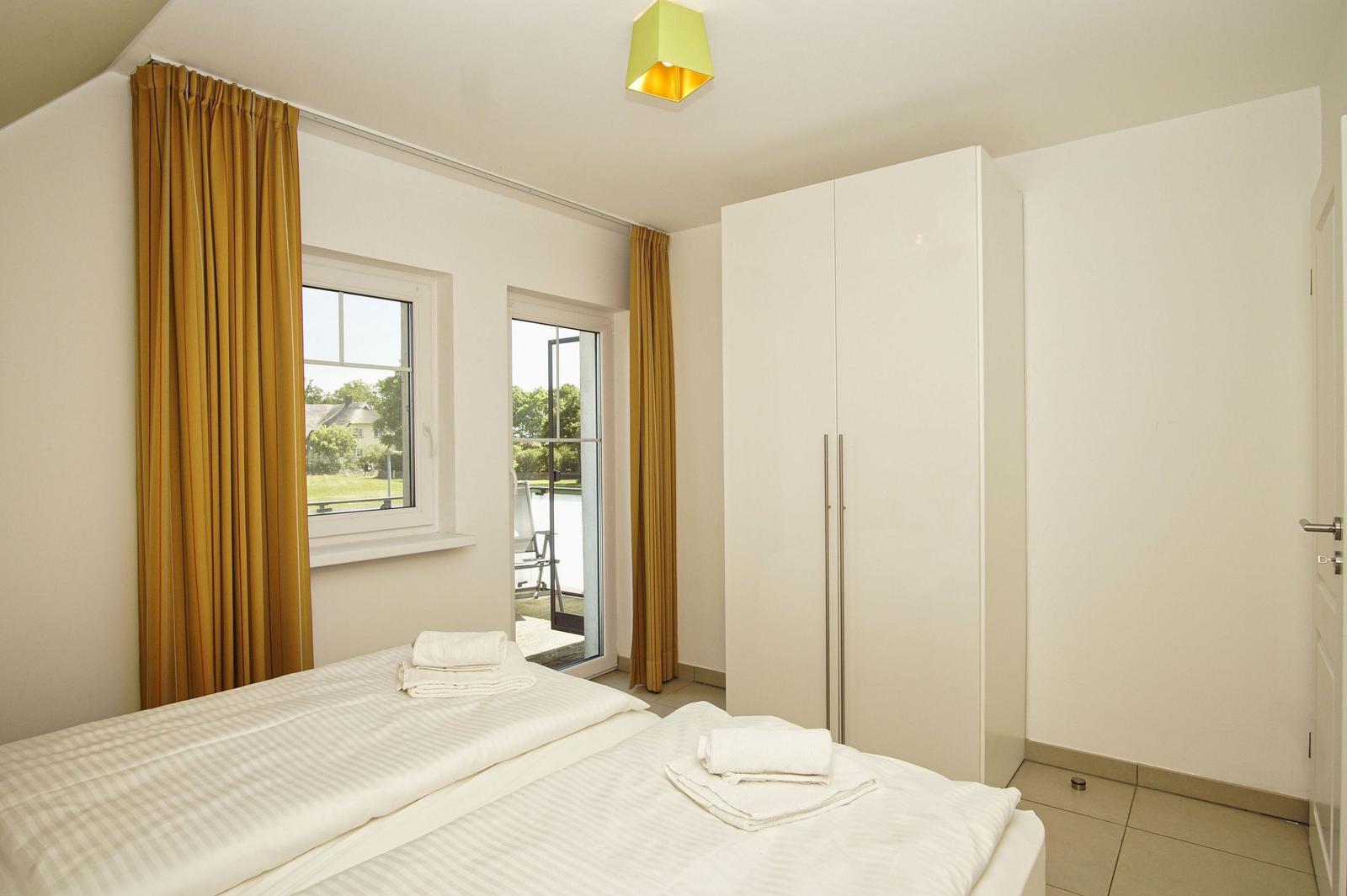 Bedroom with bed, white curtains, and view of the garden.