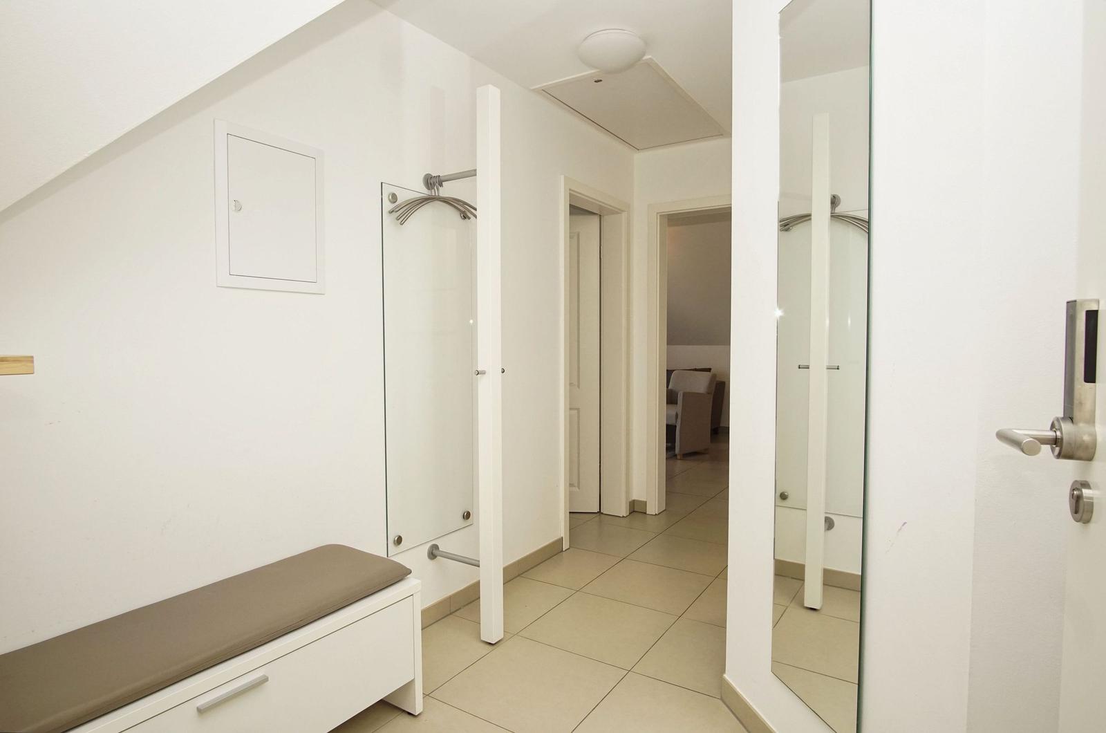 Hallway with closet, bench, and view into living area.