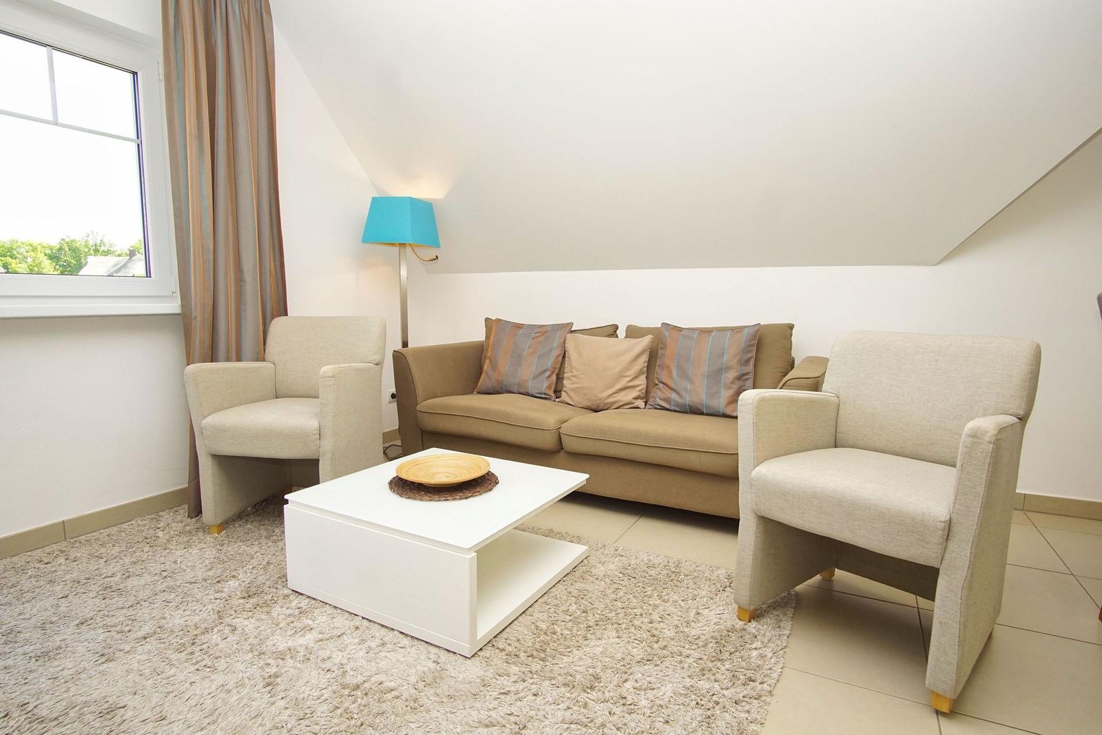 Living room with sofa, two chairs, table, and window.