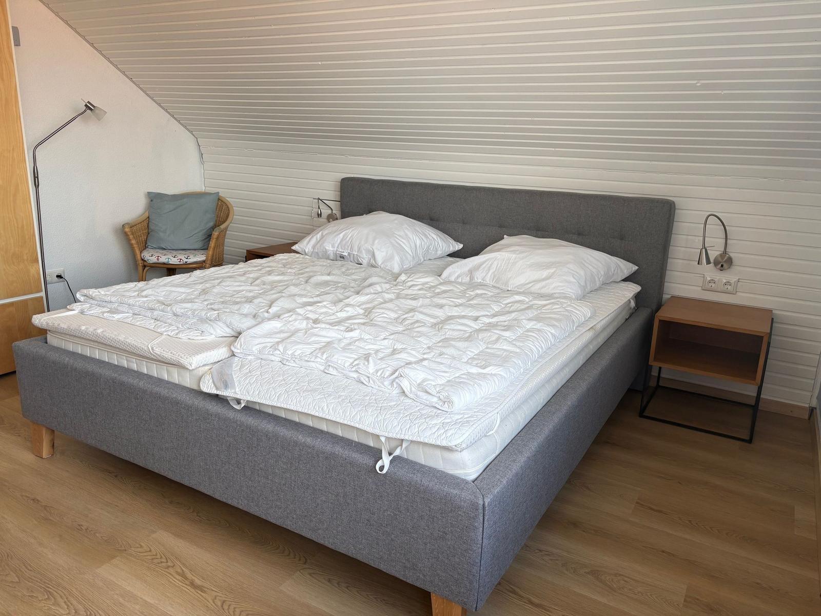 Schlafzimmer mit Doppelbett, Nachttisch und Stehlampe.