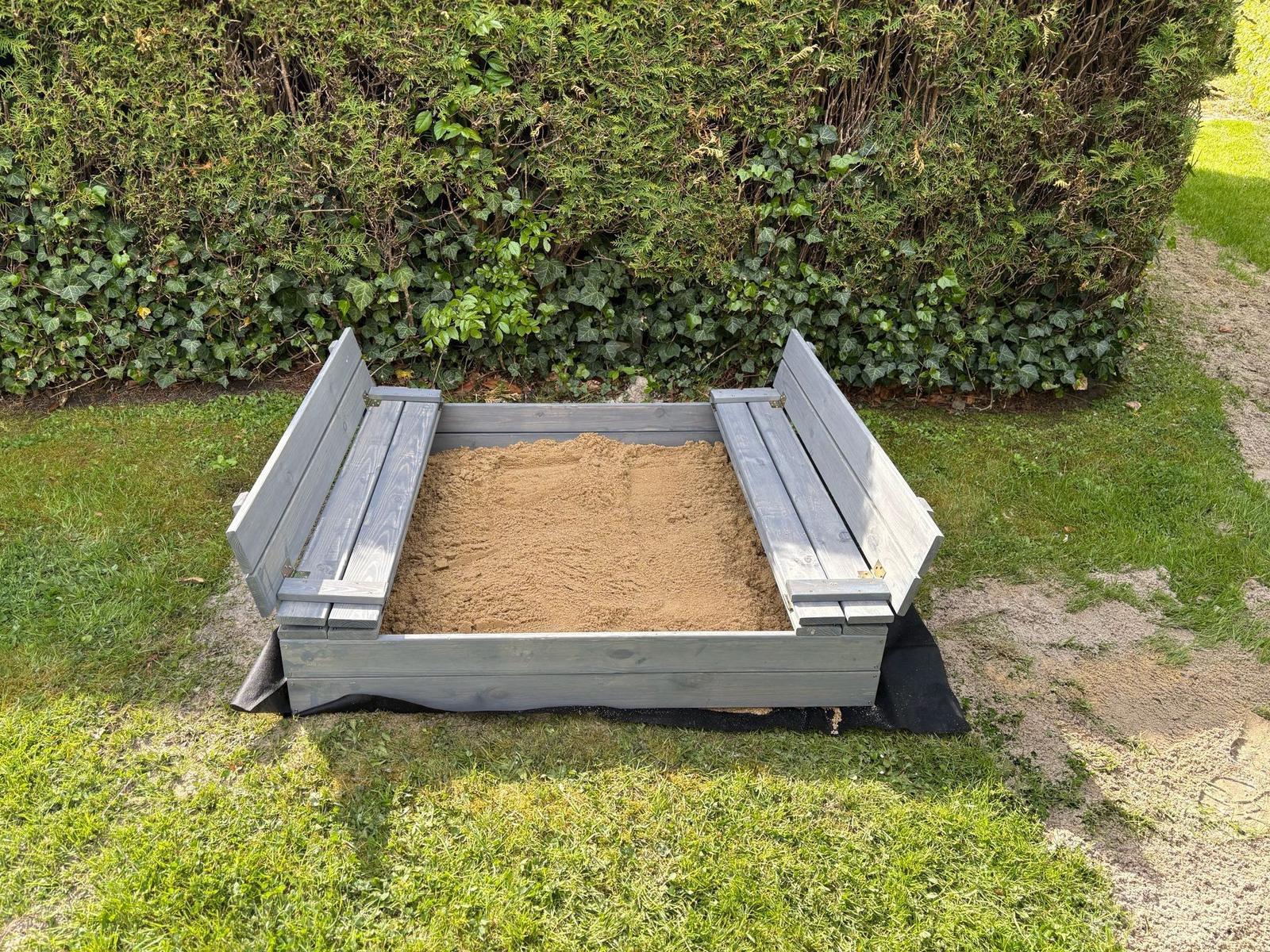 Holzrahmen-Sandkasten mit Sitzbänken im Garten