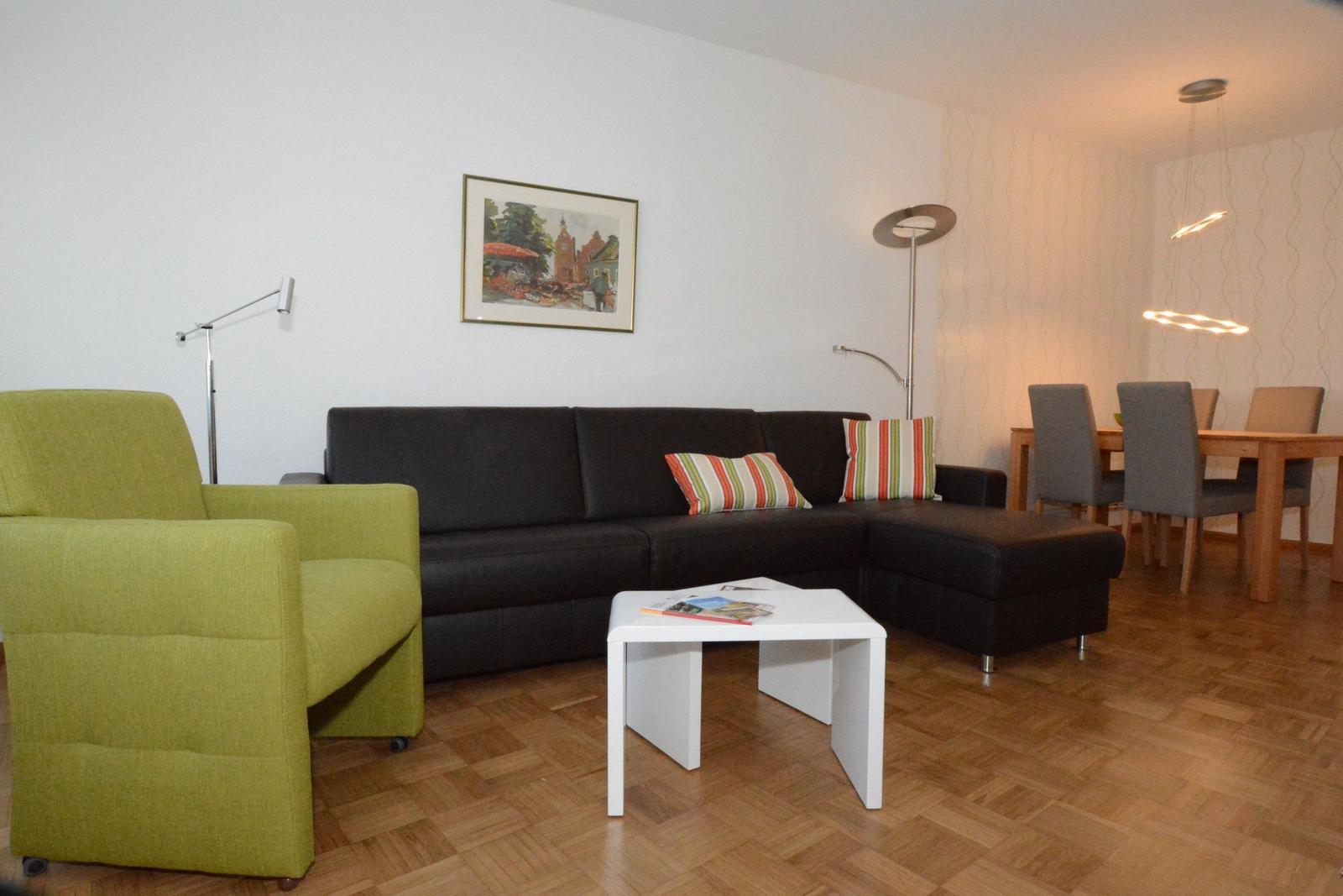 Wohn- und Essbereich mit Sofa, Sessel und Tisch.