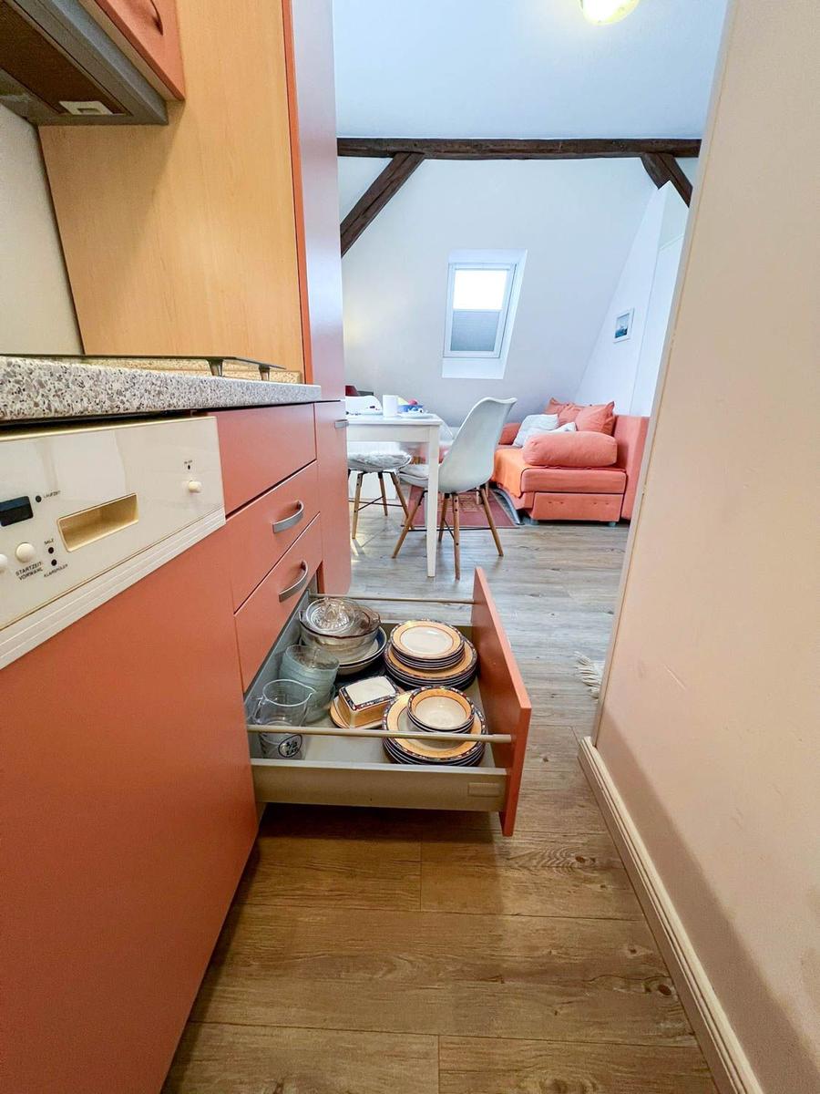 Küche mit offener Schublade und Blick in Wohnbereich mit Sofa und Tisch.