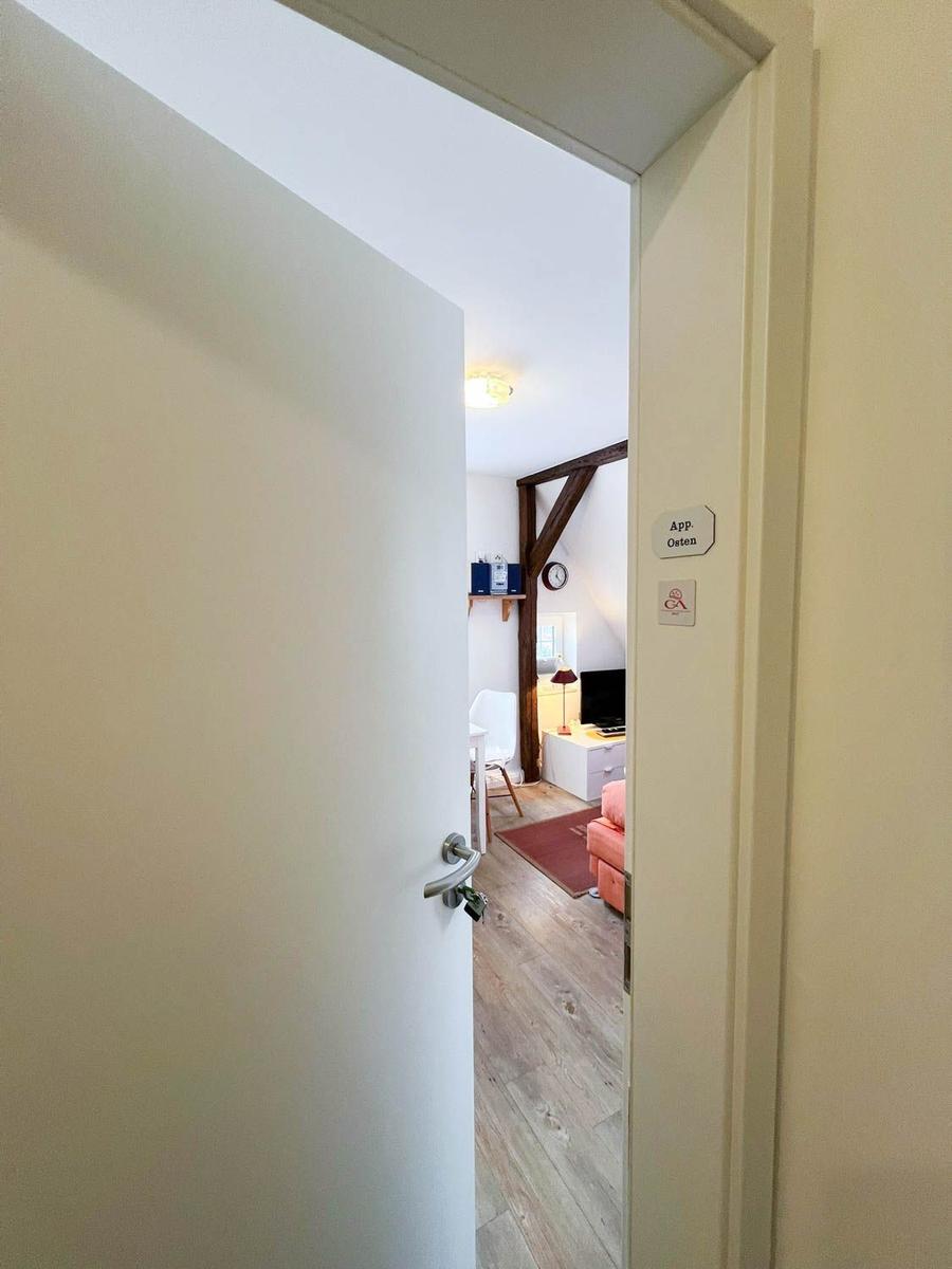 Durchgang in ein Zimmer mit Holzboden, rosa Sofa und Holzbalken.