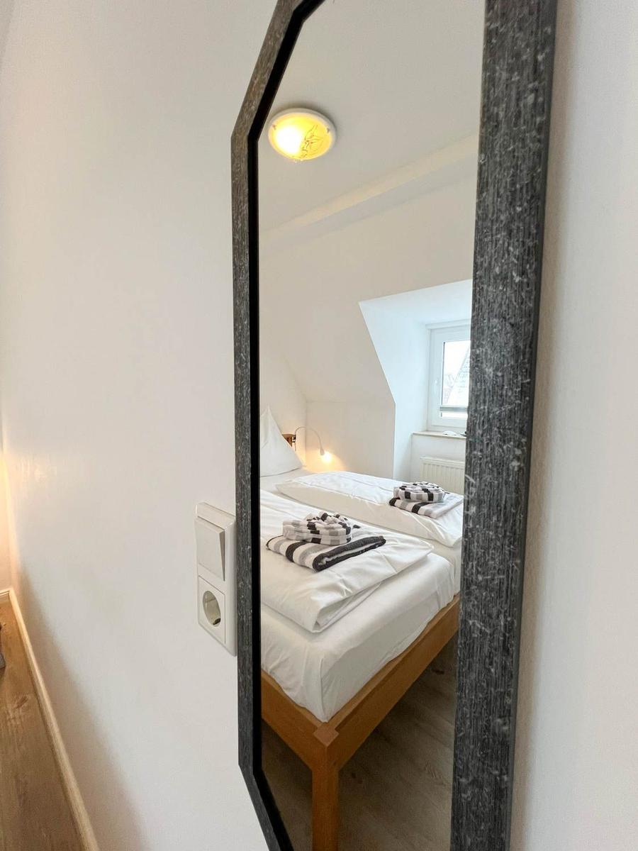 Schlafzimmer mit Spiegel, Bett und Fenster