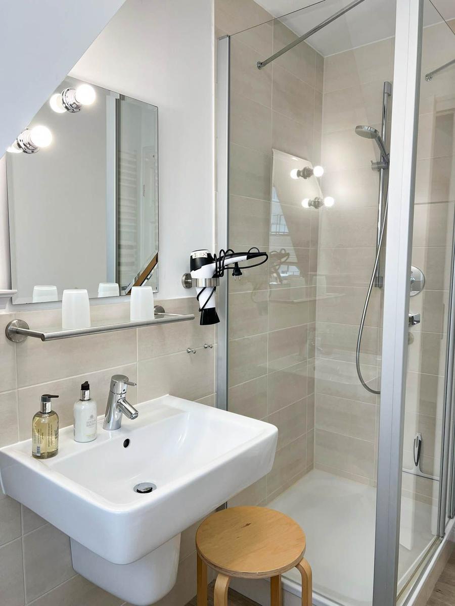 Badezimmer mit Dusche, Waschbecken und Spiegel.