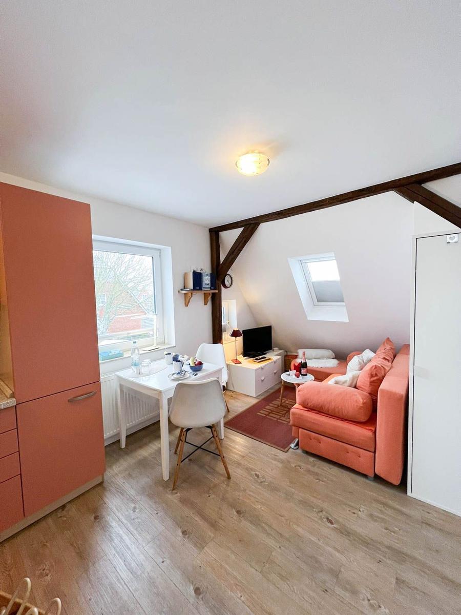 Wohnung mit Essbereich, Sofa und Dachschrägen. Holzboden und Fenster.