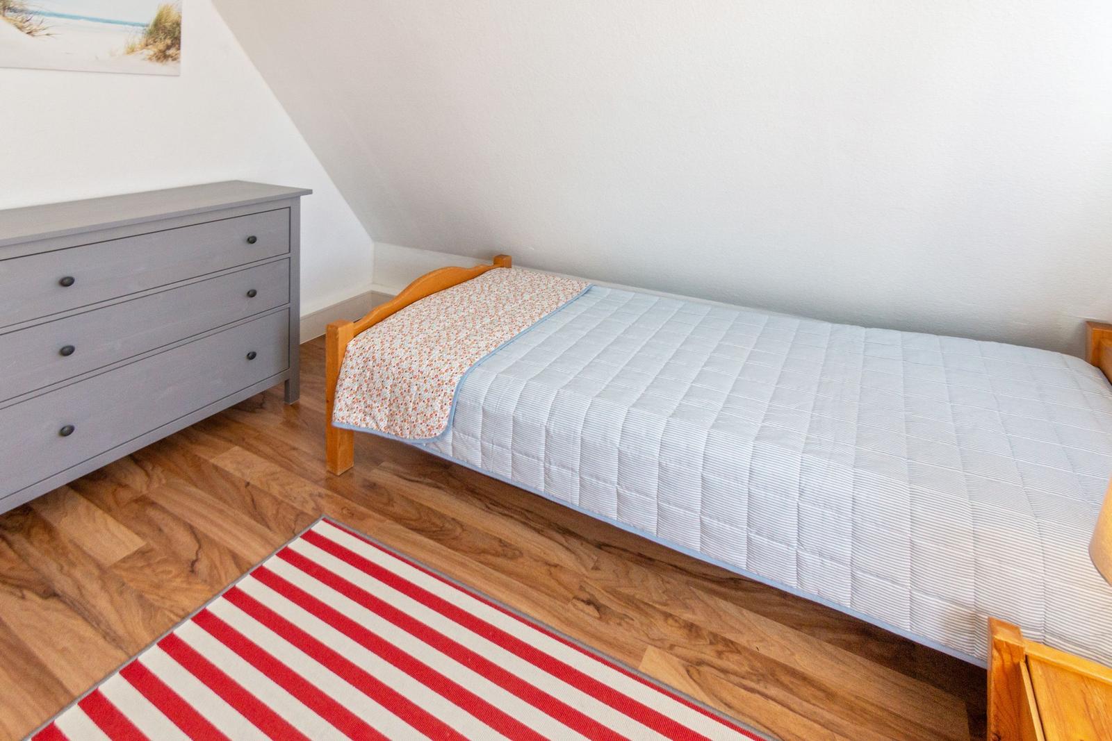 Ein Schlafzimmer mit Holzboden, einem Bett und einem Schrank.