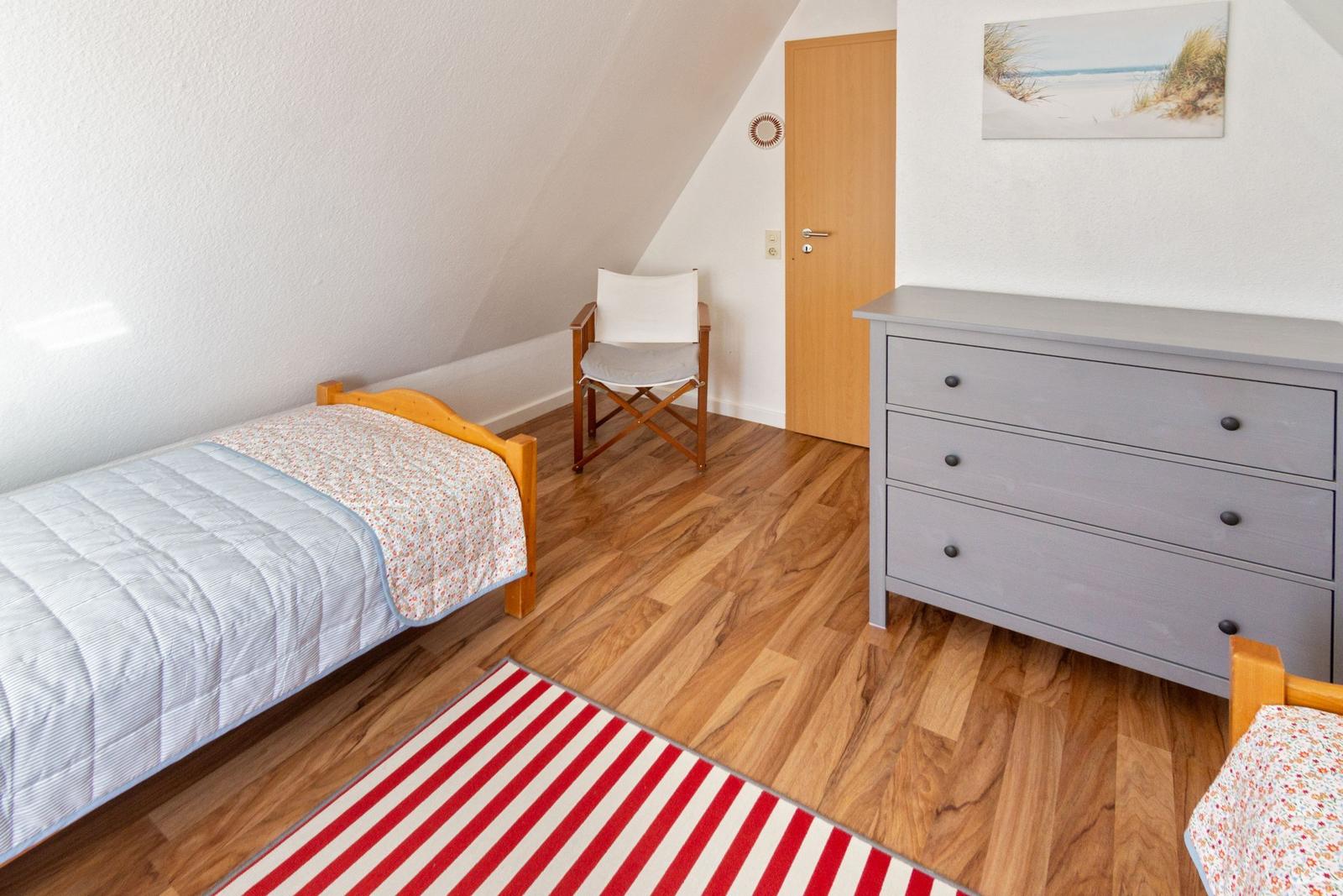 Schlafzimmer mit Doppelbett, Kleiderschrank und Stuhl auf Holzboden