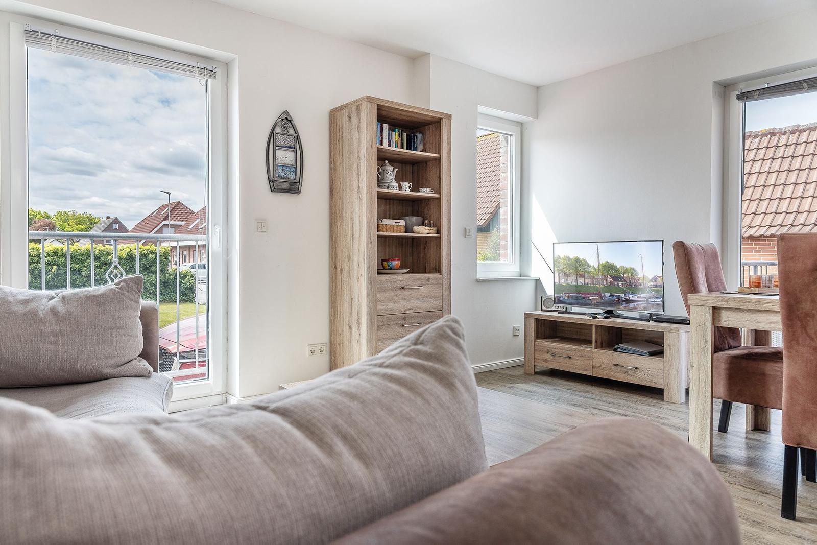 Wohnzimmer mit Sofa, Fernseher und Essbereich. Durchgang zur Terrasse mit Blick auf die Umgebung.