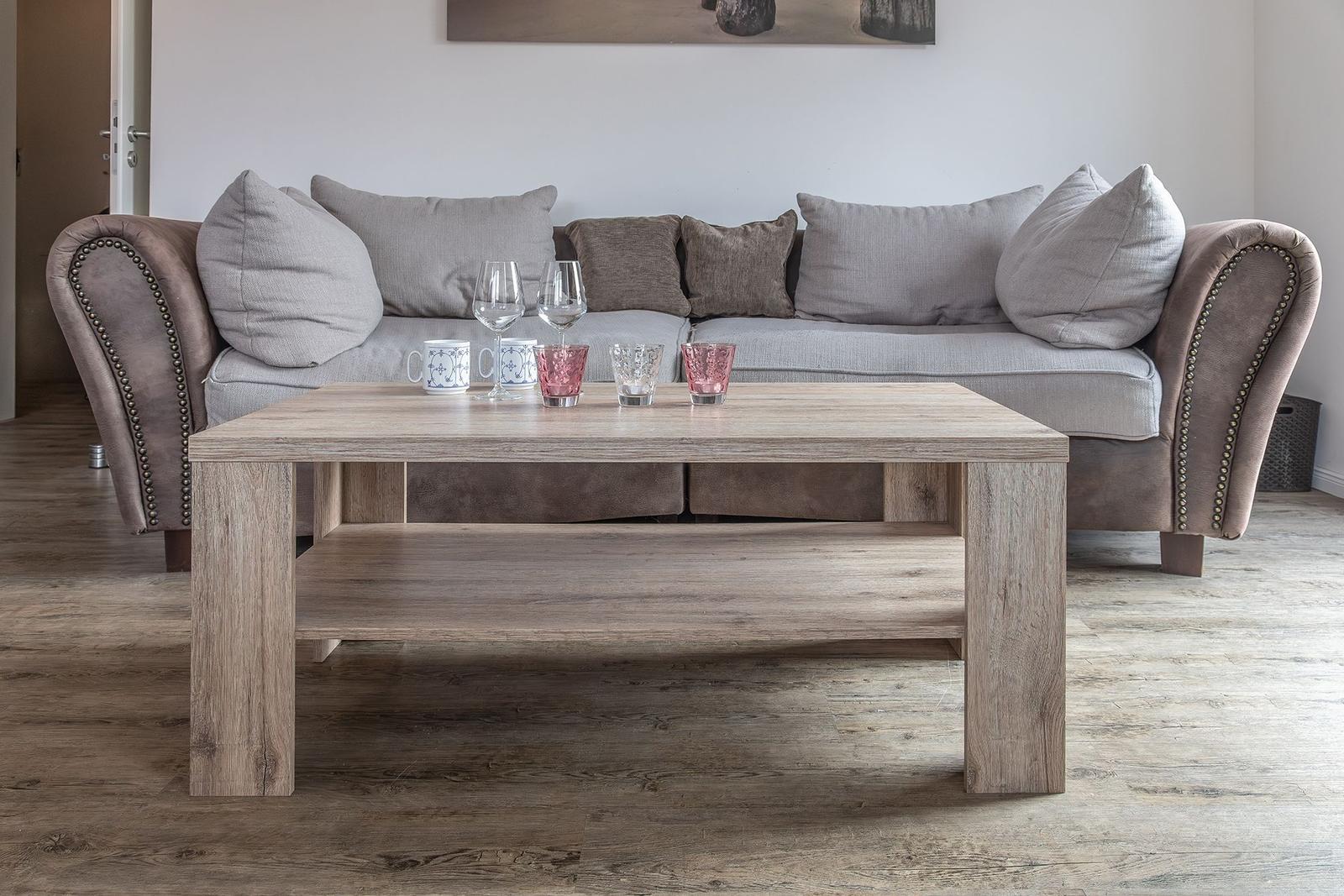 Ein Wohnzimmer mit einem Sofa, einem Holztisch und Gläsern.