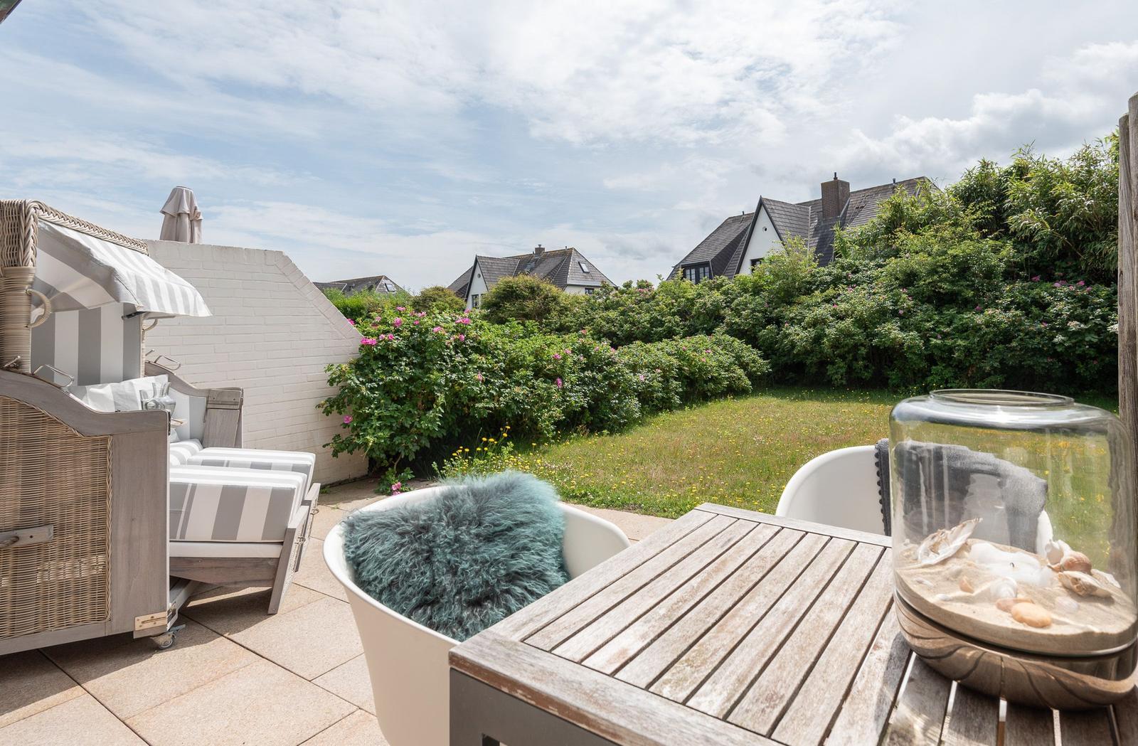 Terrace with table, chairs, and view of garden and houses.