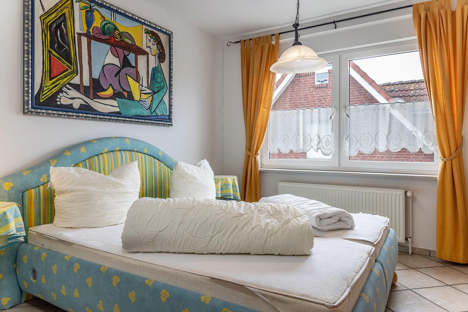 Schlafzimmer mit Bett, Fenster und Wandbild.