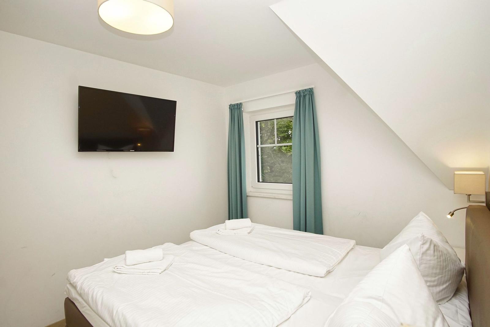 Zimmer mit Doppelbett, Fenster, TV und Stehlampe