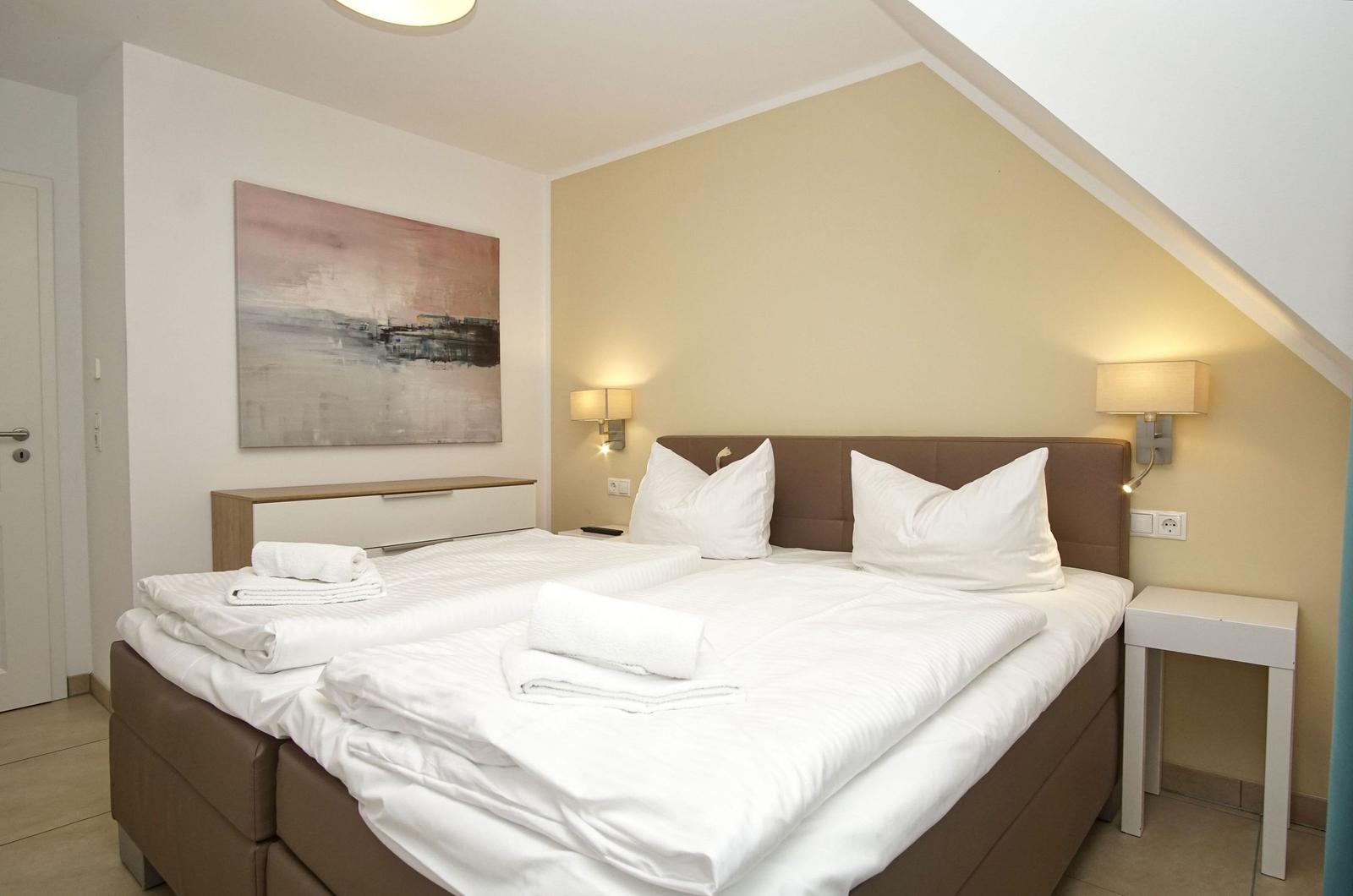 Schlafzimmer mit Doppelbett, Nachttischen und Wandbild.