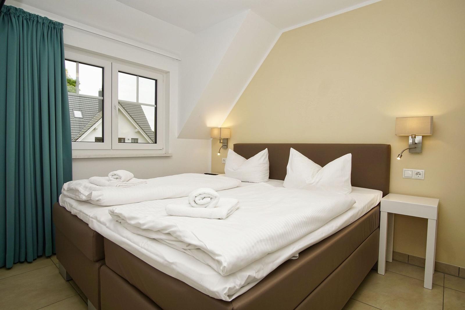 Bedroom with double bed, window, and nightstand.