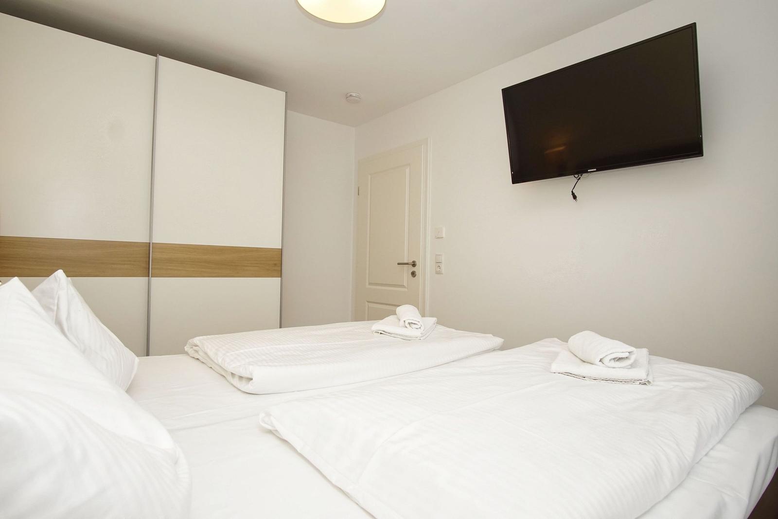 Bedroom with bed, wardrobe, and wall-mounted TV.