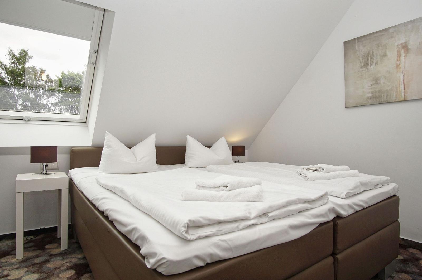 Bedroom with double bed, window, and wall art.