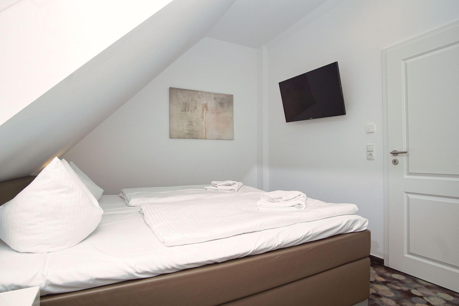 Bedroom with sloped ceiling, bed, TV, and door