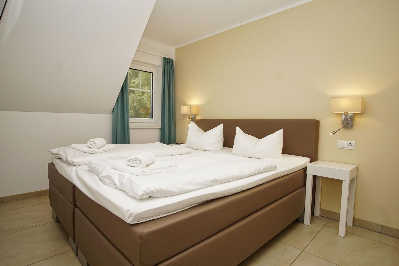 Schlafzimmer mit Doppelbett, Fenster und Nachttisch