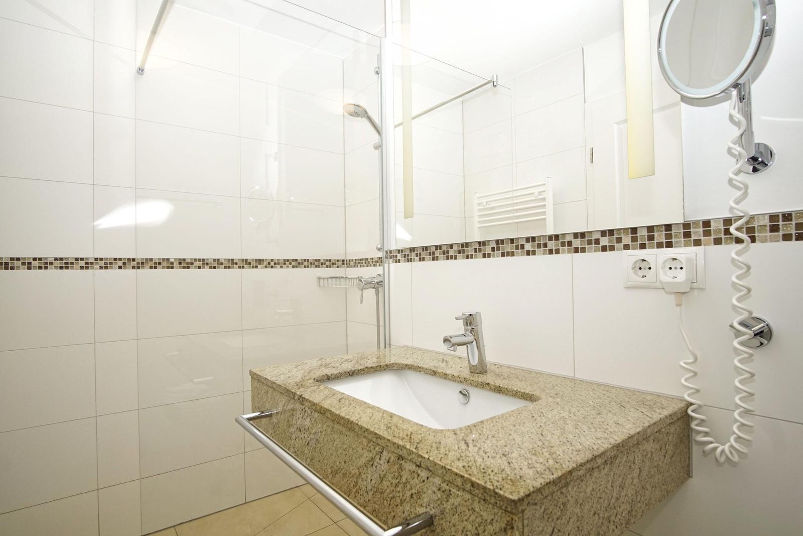 Badezimmer mit Dusche, Waschbecken und Spiegel