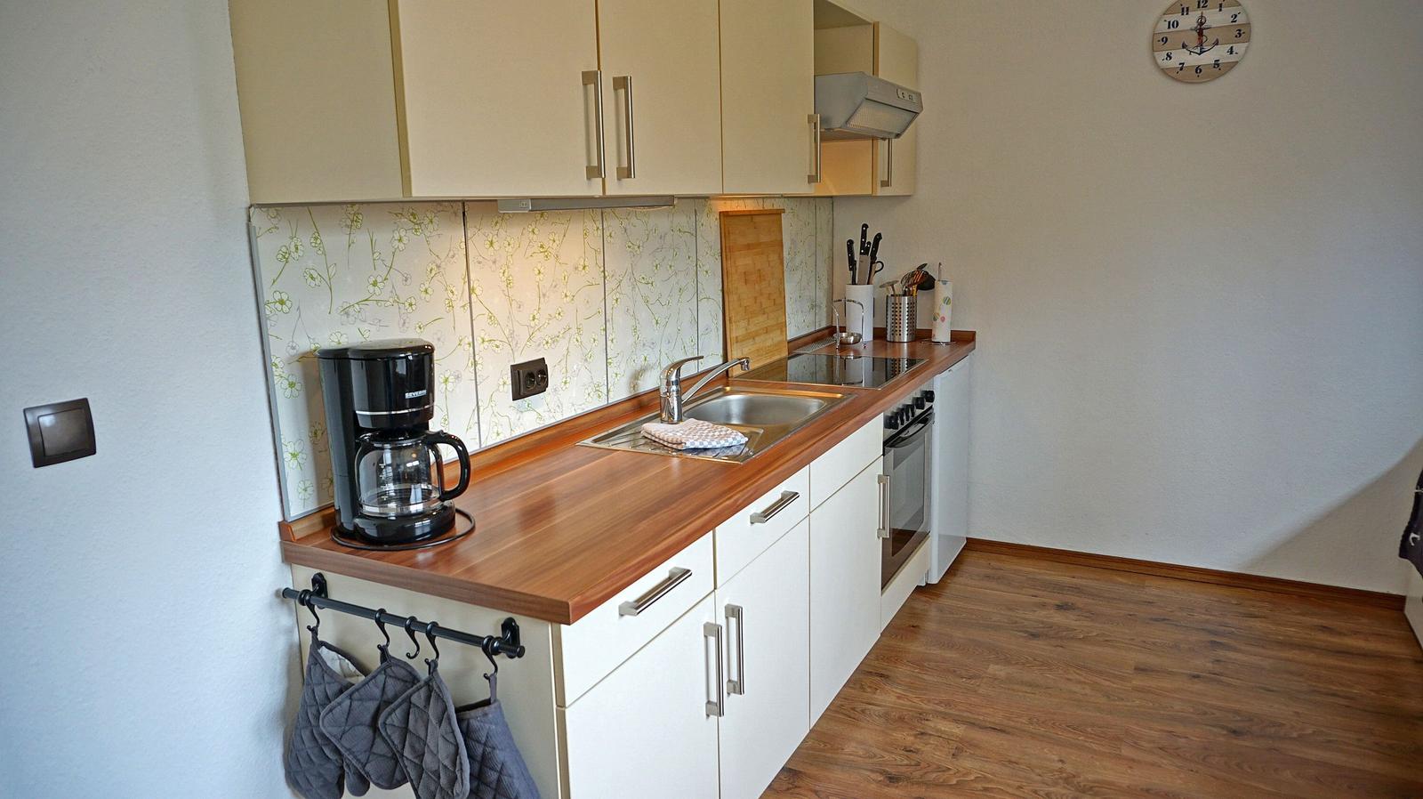 Küche mit Holzoberfläche, Spüle, Kaffeemaschine und Küchenschränken.