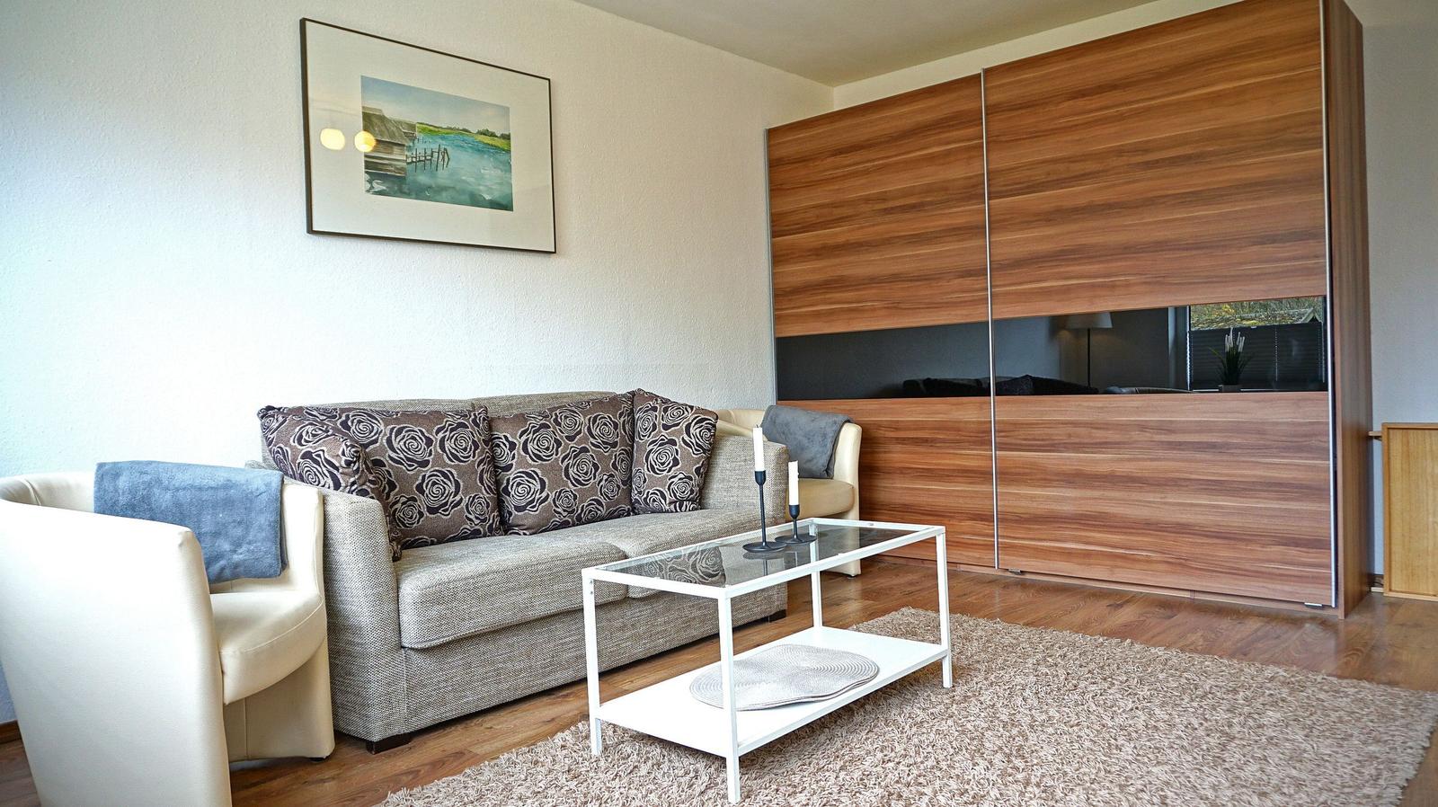 Wohnzimmer mit Sofa, Couchtisch und Holzwand. Bild an der Wand.