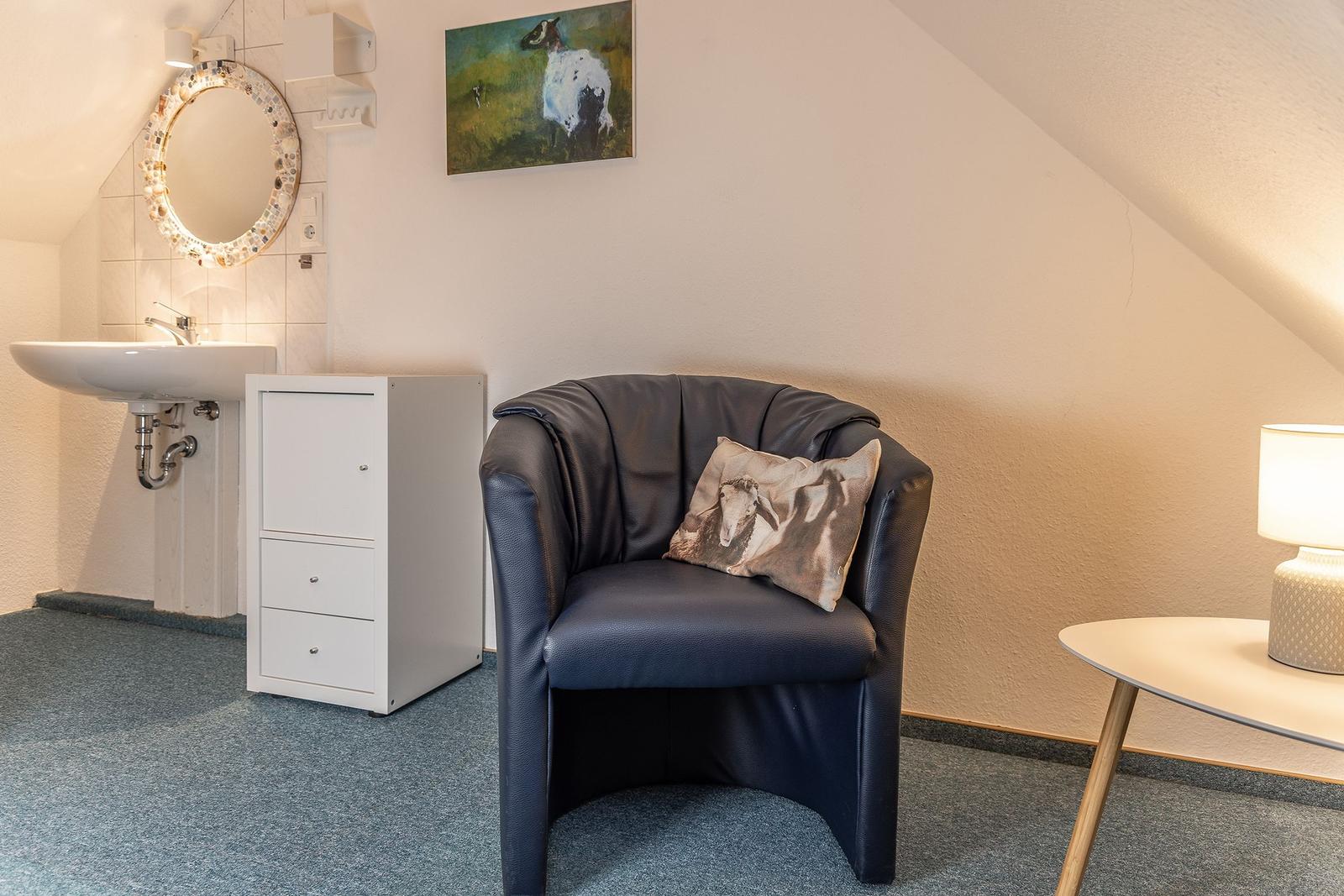 Schwarze Ledersessel mit Kissen, Waschbecken und Spiegel an der Wand.
