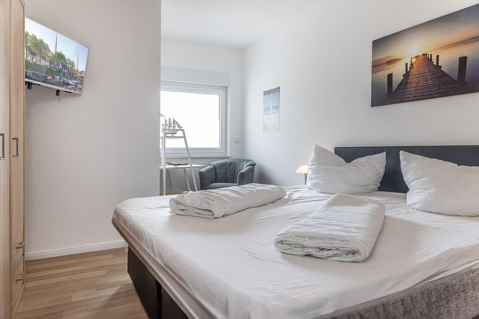 Schlafzimmer mit Bett, Fernseher und Fenster