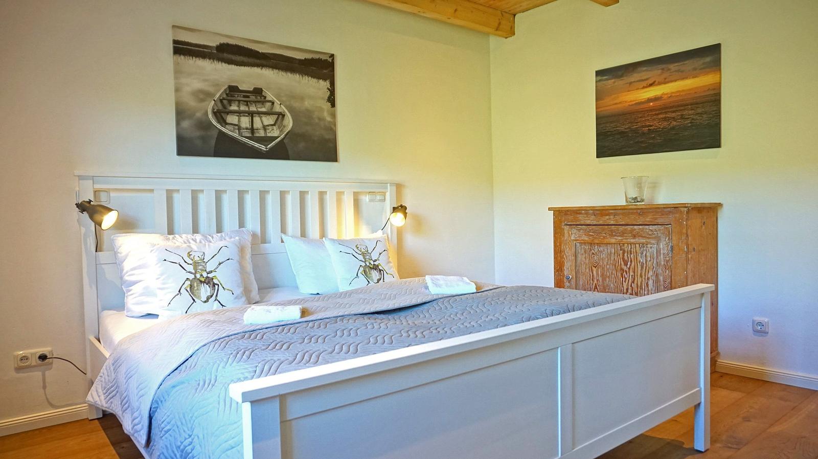 Schlafzimmer mit weißem Bett, Holzboden und Wandbildern