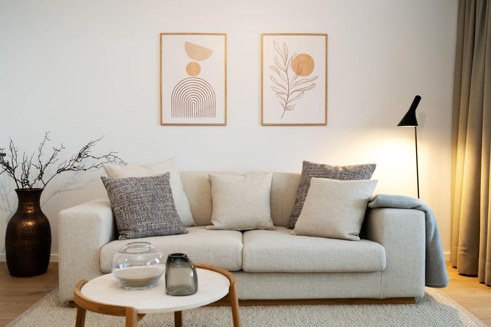 Ein Wohnzimmer mit Sofa, Kissen, Wandbildern und Beistelltisch.