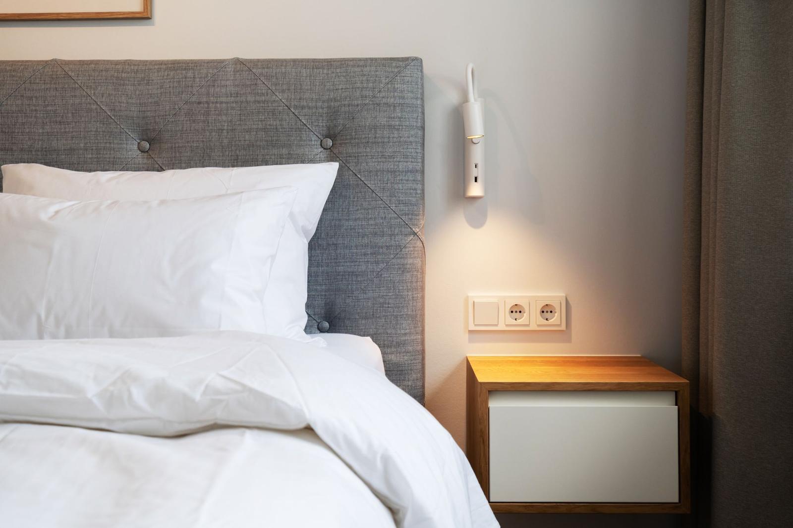 Bettkopfteil mit Knopfverzierung, Nachttisch und Wandlampe