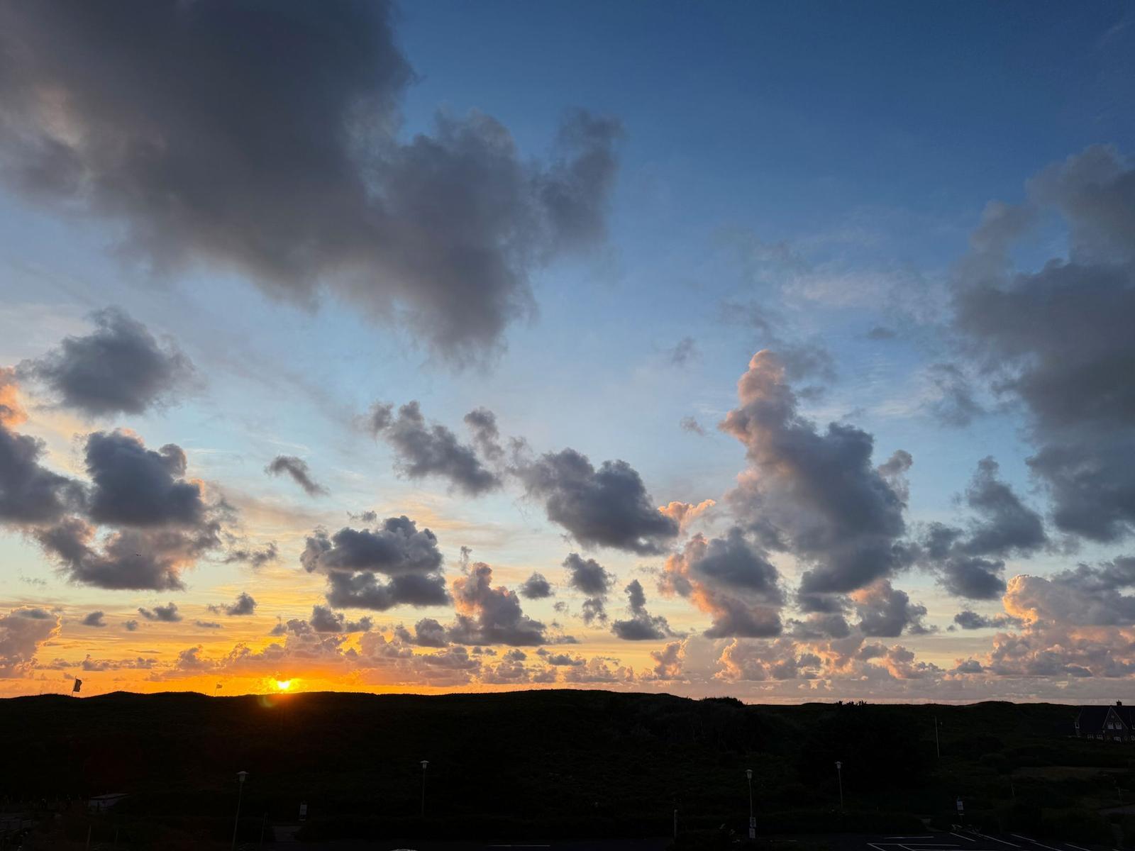 Sonnenuntergang mit bewölktem Himmel über Hügeln