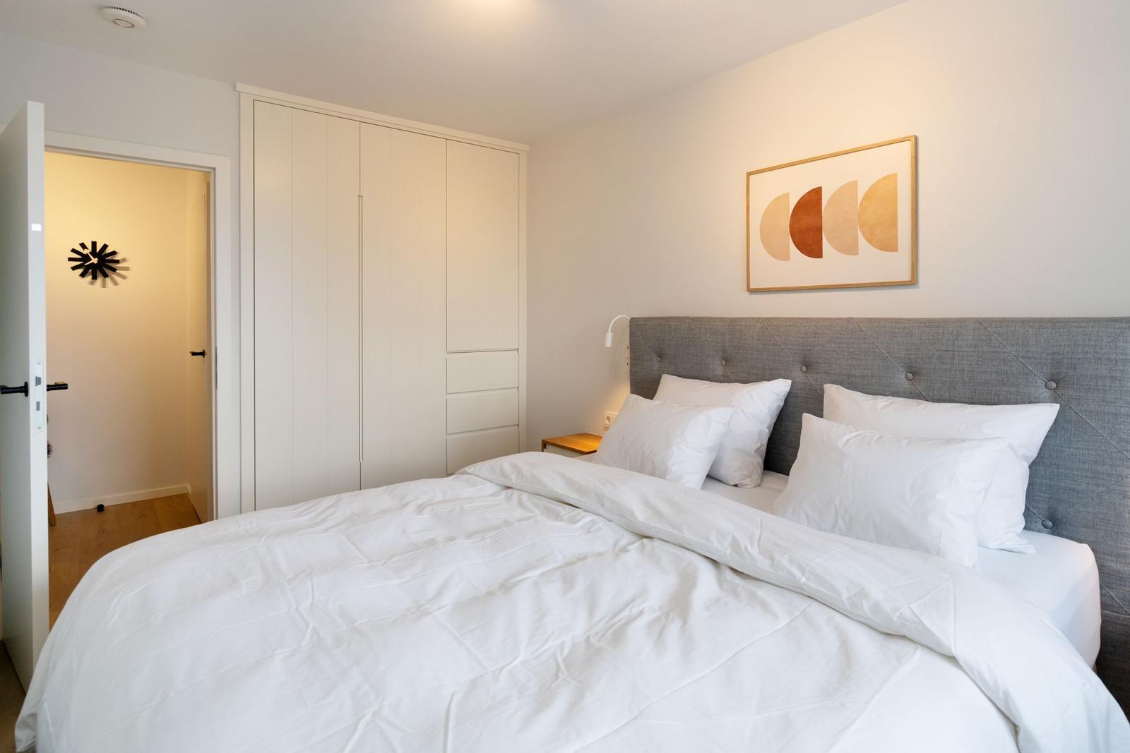 Schlafzimmer mit Bett, Kleiderschrank und Wandbild