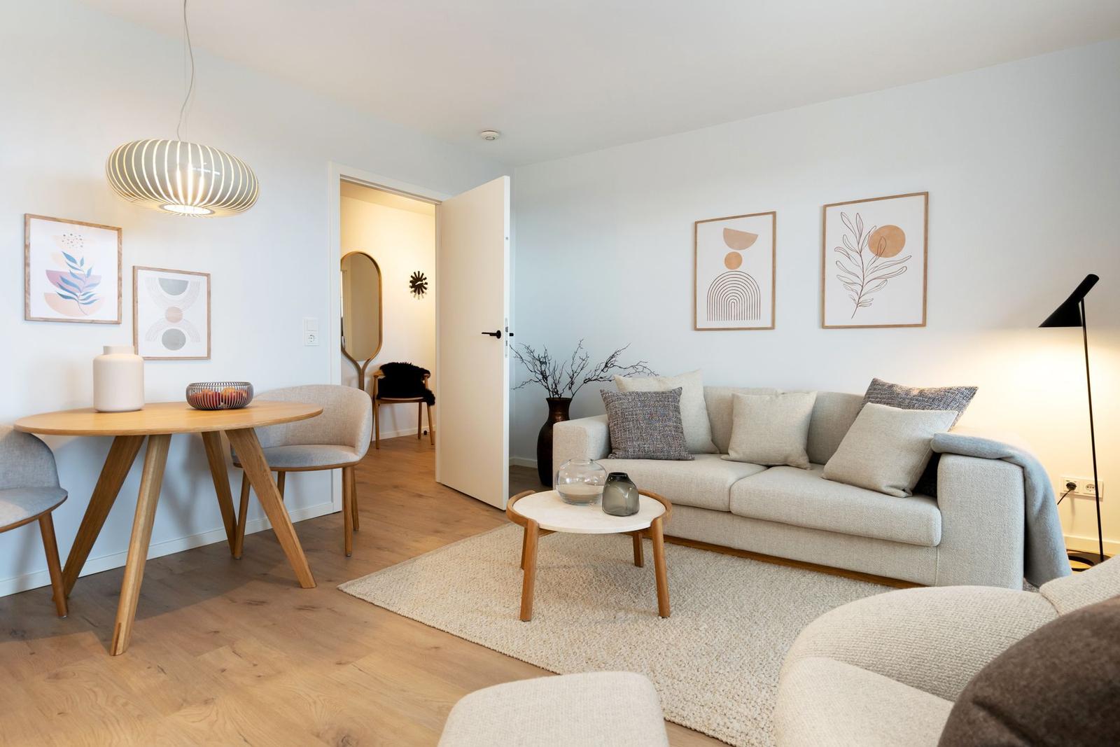 Wohn- und Essbereich mit Sofa, Tisch und Wandbildern.