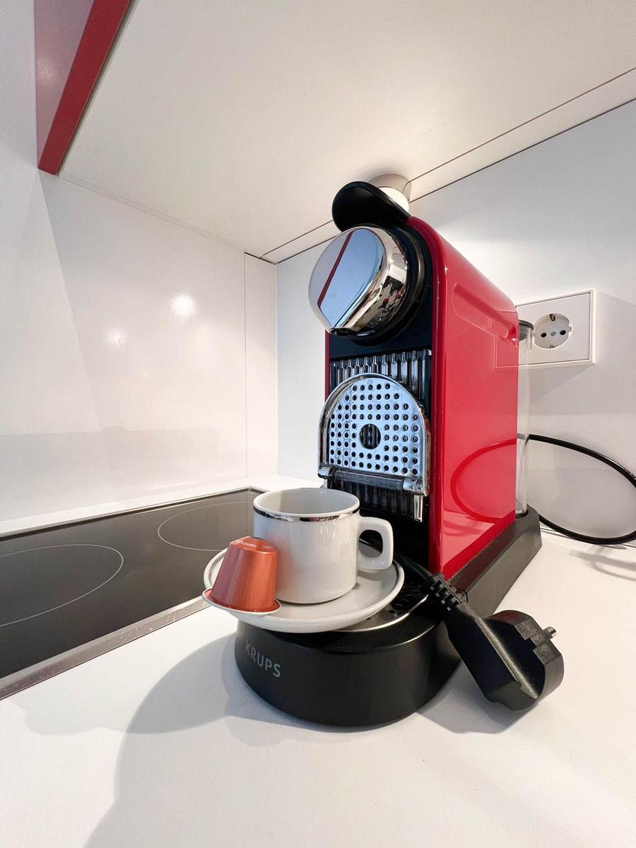 Roter Kaffeemaschine mit Tasse und Kapsel auf Küchenarbeitsplatte