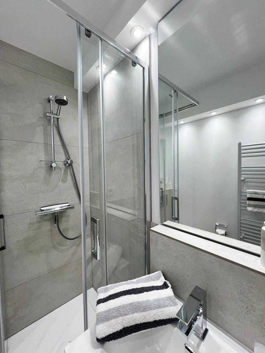 Dusche mit Glaswand, Spiegel und Handtuch auf Waschbecken
