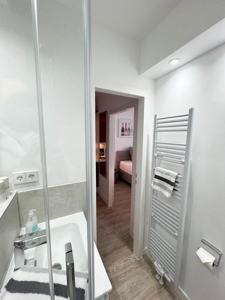 Badezimmer mit Dusche und Heizkörper, Blick in Schlafzimmer mit Bett und Wandbild.