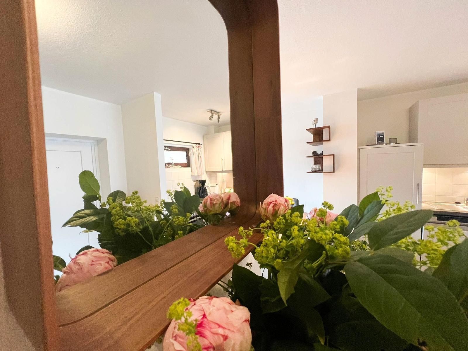 Spiegel reflektiert Küche und Flur mit Blumen auf Holzbank