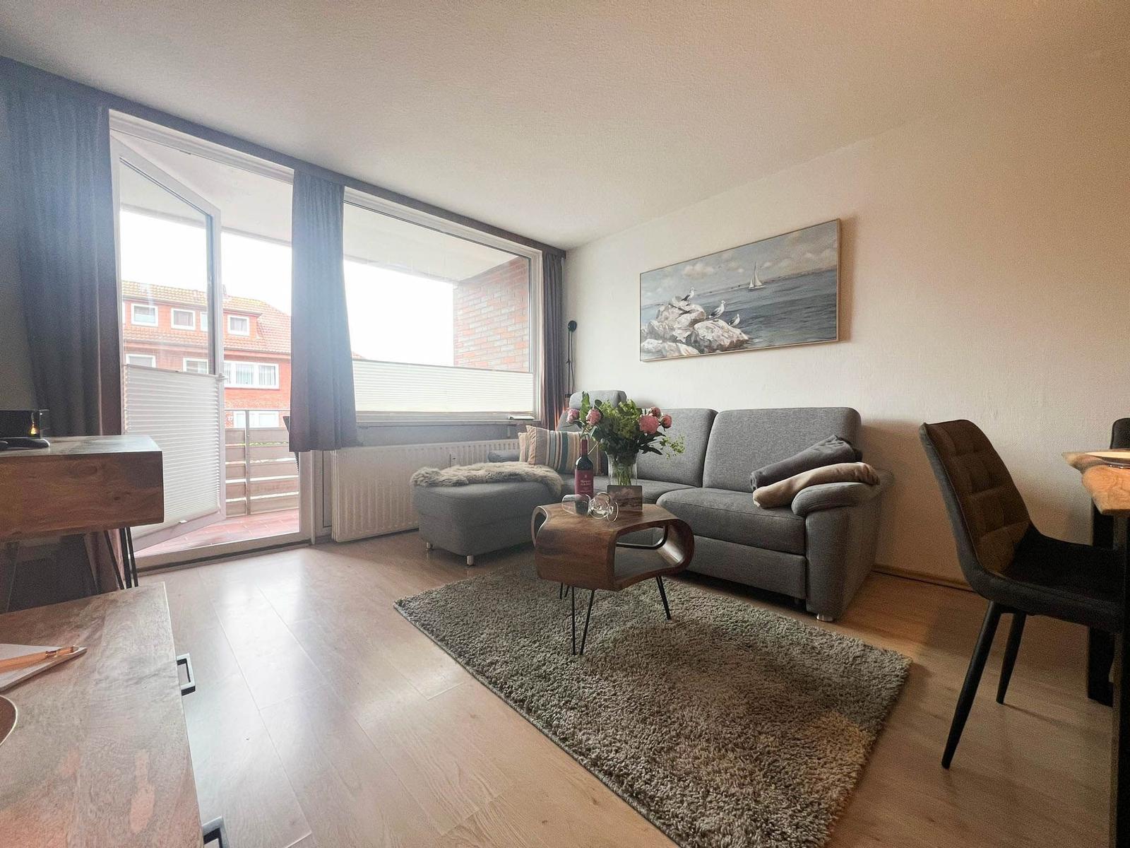 Wohnzimmer mit Sofa, Tisch und Blick auf Balkon.