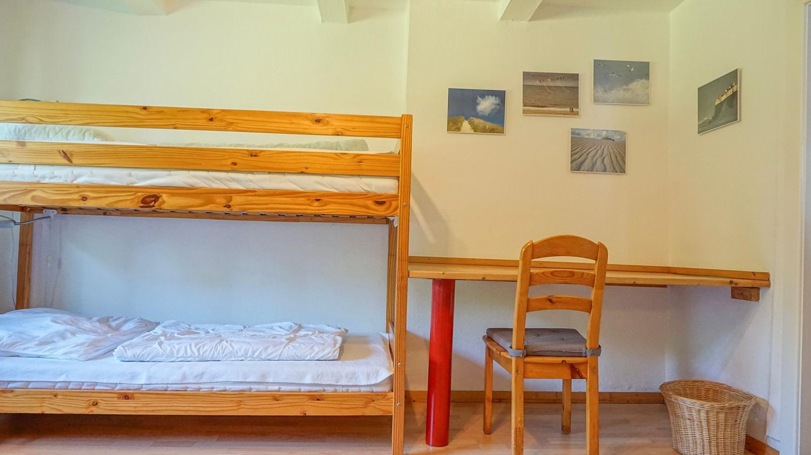 A room with a wooden bed and a desk with a chair.
